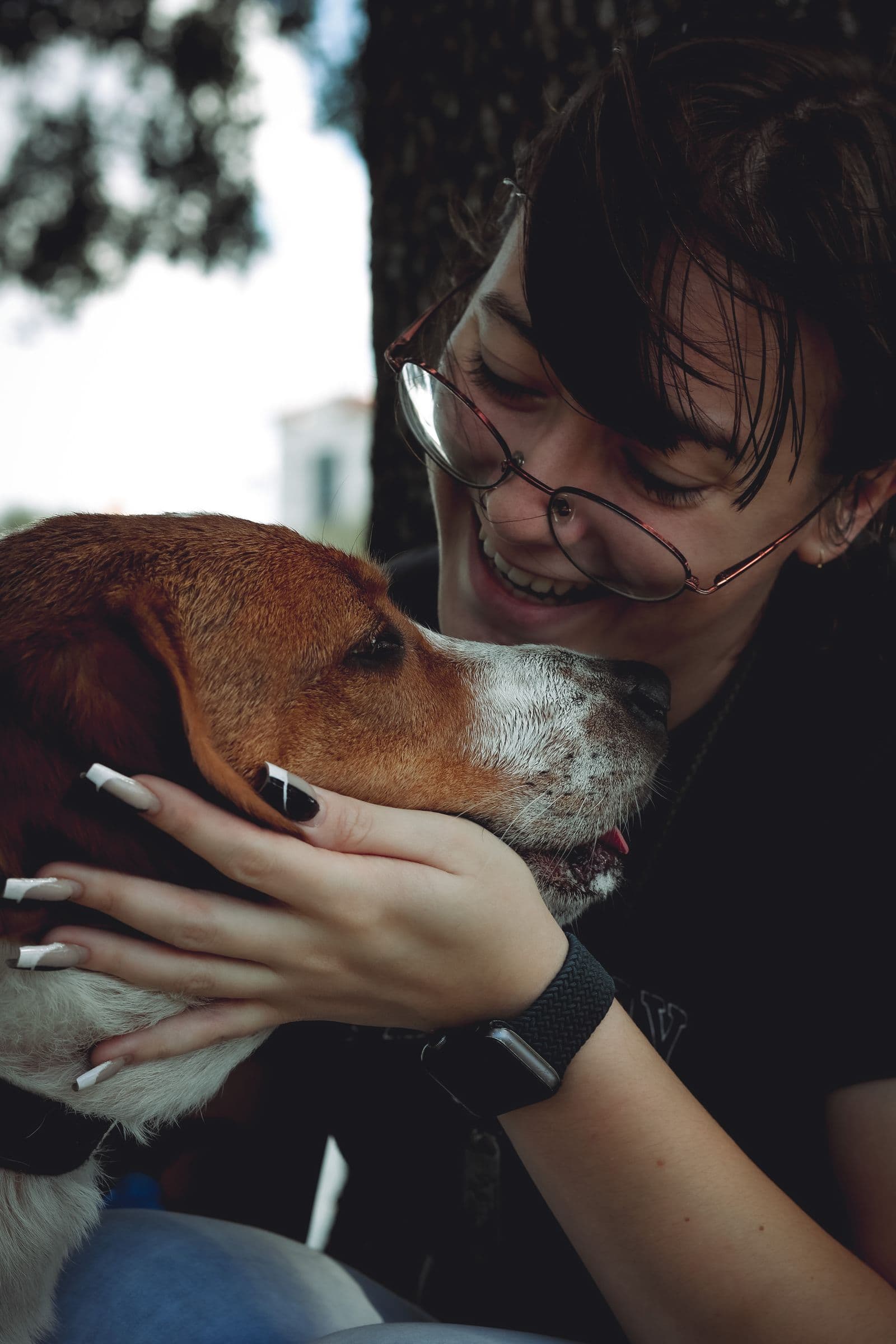 Uma mulher abraçando um cachorro e sorrindo para ele
